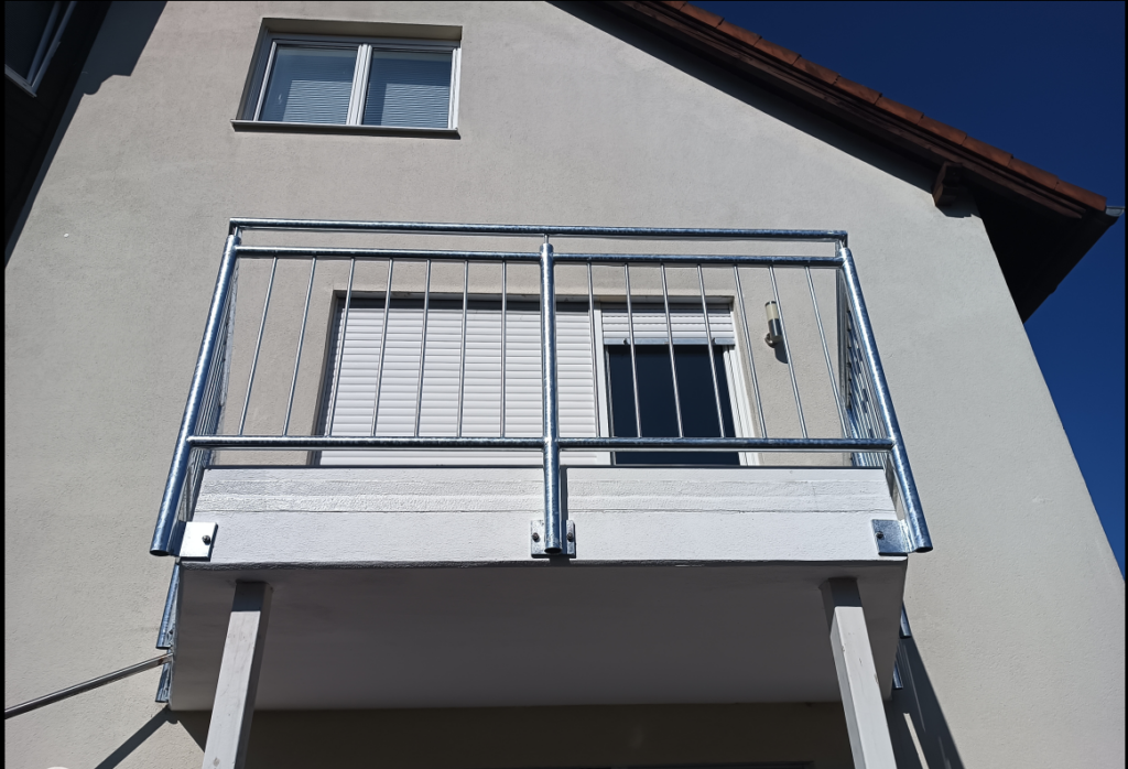 Verzinktes Balkongeländer mit senkrechten Stäben an einer Hausfassade in Wintersdorf
