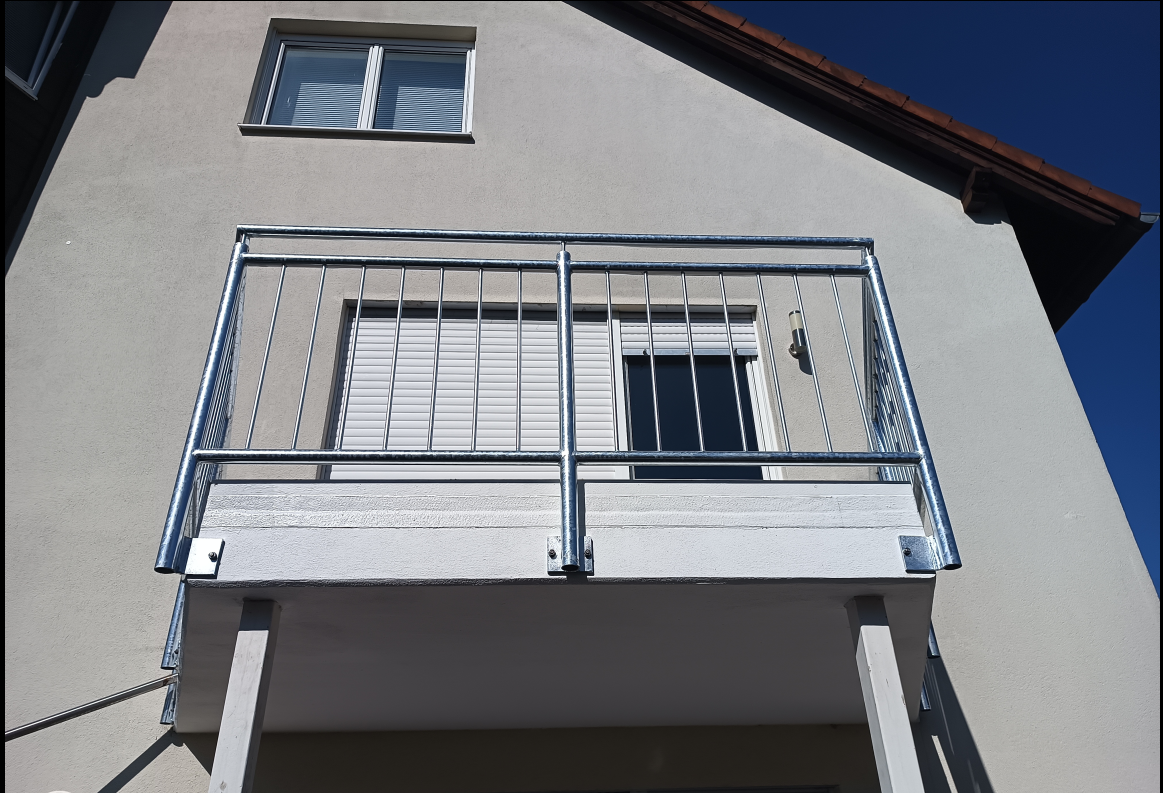 Verzinktes Balkongeländer mit senkrechten Stäben an einer Hausfassade in Wintersdorf