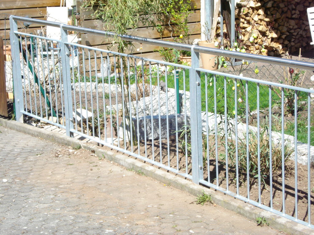 Verzinkter Metallzaun mit senkrechten Stäben als Beeteinfassung im Garten