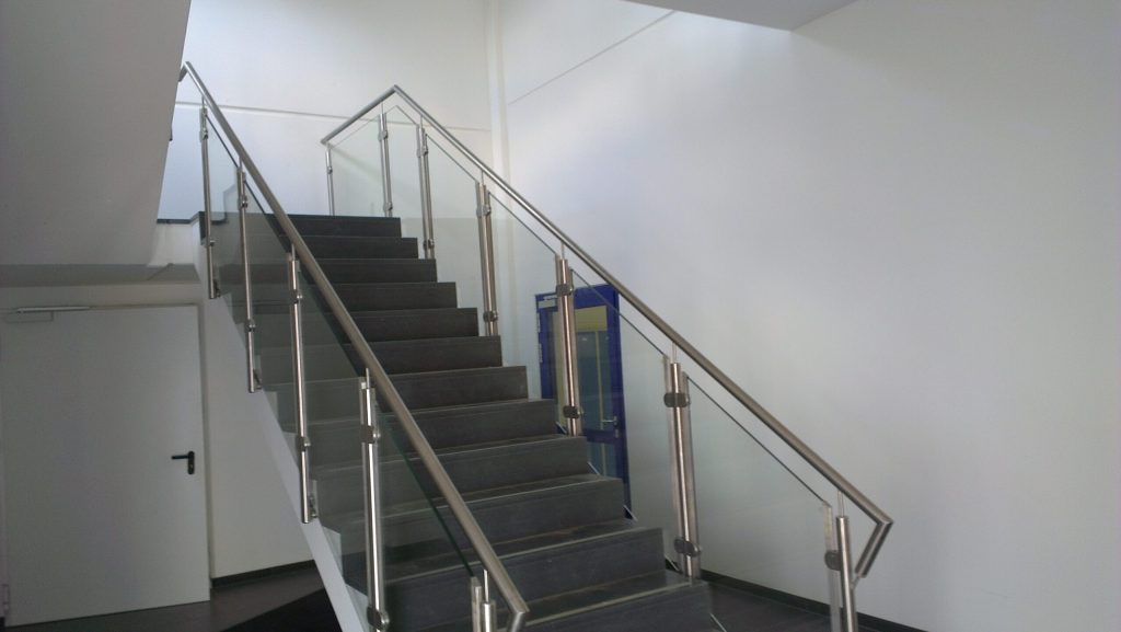 Innen liegendes Edelstahlgeländer mit Glasfüllung an einer Treppe in einem Gewerbebau