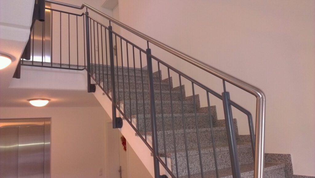 Innentreppe mit Granitstufen und Metallgeländer mit Edelstahl-Handlauf in einem Treppenhaus