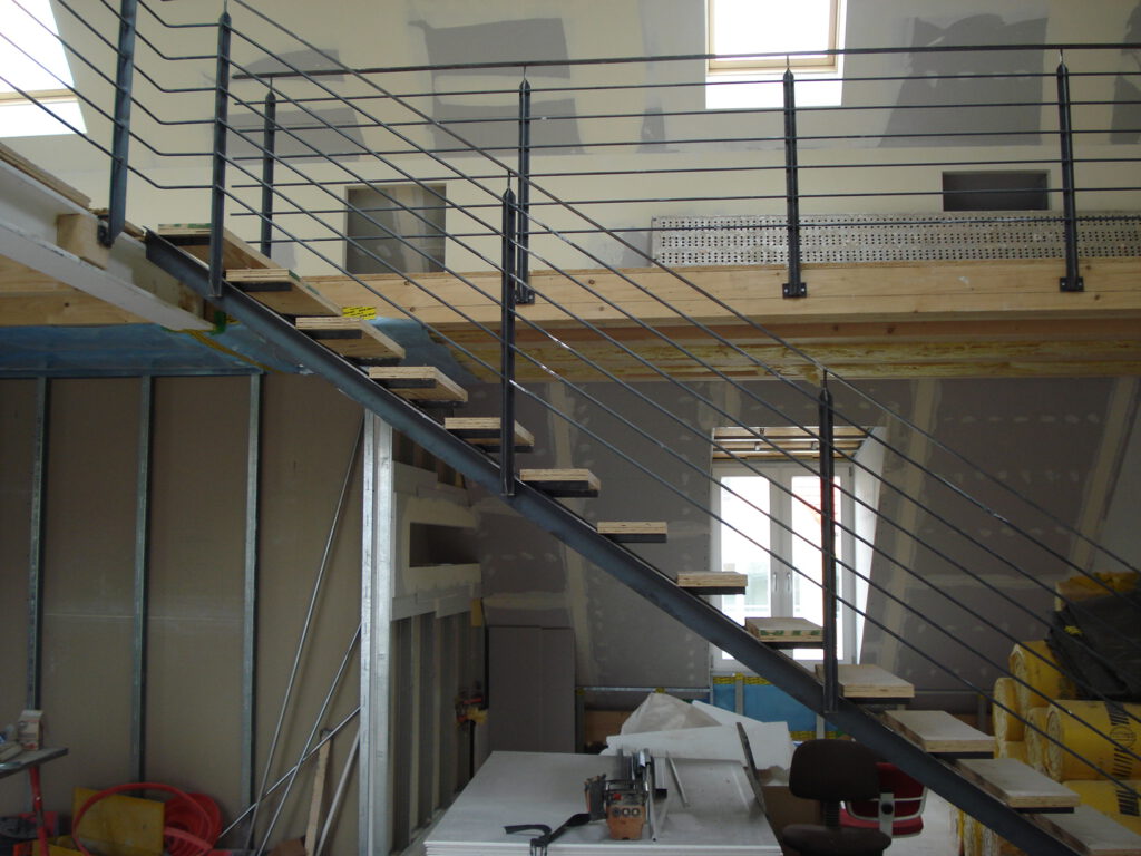 Freitragende Stahltreppe mit Seilgeländer in einem ausgebauten Dachgeschoss